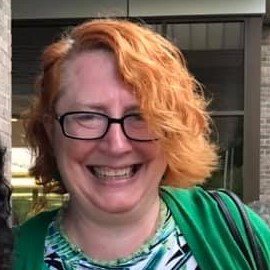 Photo of library director "Mary Harrison" smiling in front a glass window.